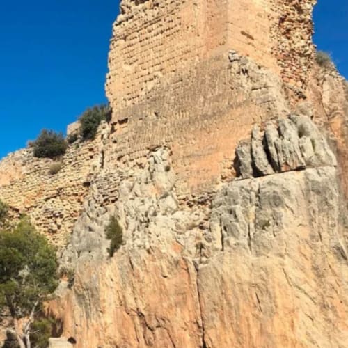 Ruinas de antigua torre de piedra en Rustikalpuente, España con cielo azul despejado y vegetación del paisaje desértico