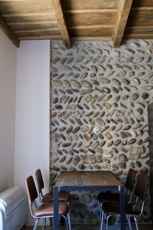 Rustikaler Essbereich mit freiliegenden Holzbalken, Steinwand und modernem Tisch mit Lederstühlen im Borgovivobg Bergamo