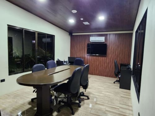 Moderna sala de conferencias del Contenedores Boutique Hotel con mesa ovalada, sillas azules y paredes con paneles de madera