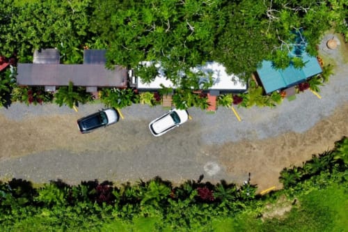 Vista aérea del Contenedores Boutique Hotel en Costa Rica con autos estacionados, vegetación exuberante y arquitectura moderna de contenedores