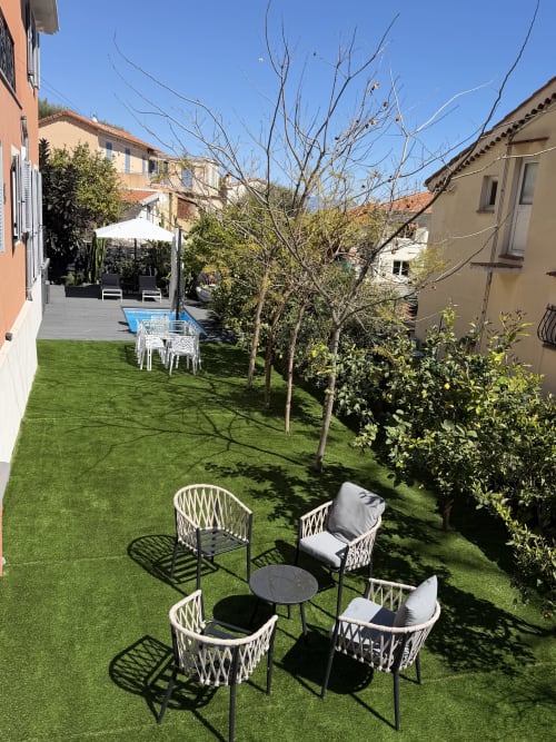 Jardin ensoleillé de la villa Blue Vista à Beausoleil avec chaises longues blanches, petite table et aménagement paysager