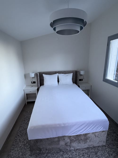 Chambre moderne avec vue sur la mer à Villa Monaco, Blue Vista Beausoleil. Lit double aux draps blancs, luminaire suspendu,