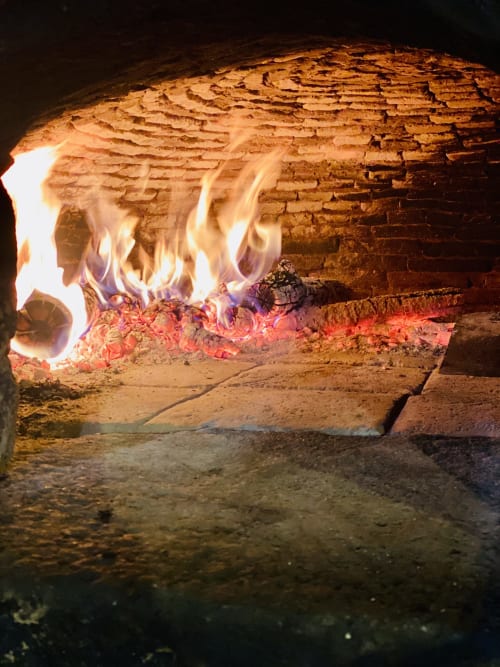 Cheminée de la villa Le 1830 à Églisolles avec flammes et braises rougeoyantes dans l'âtre en brique