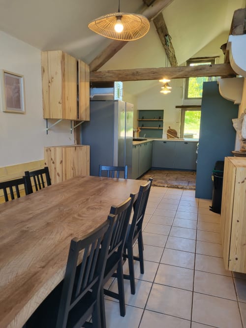 Modern cottage kitchen dining area at Domaine Des Forges De La Vache with wooden table, black chairs, and blue cabinetry.