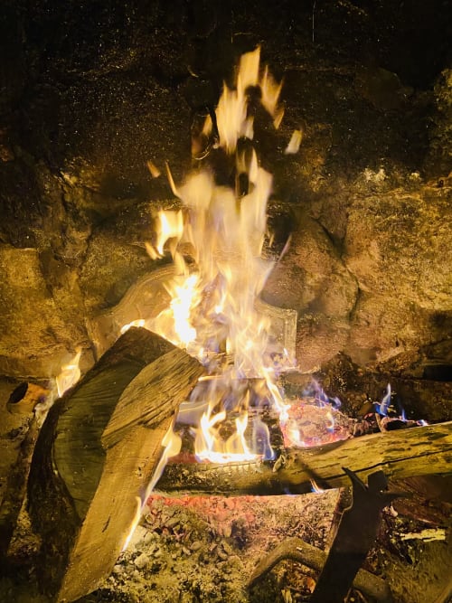 Feu de camp scintillant au jardin de la villa Le 1830 à Églisolles, bûches de bois et flammes nocturnes