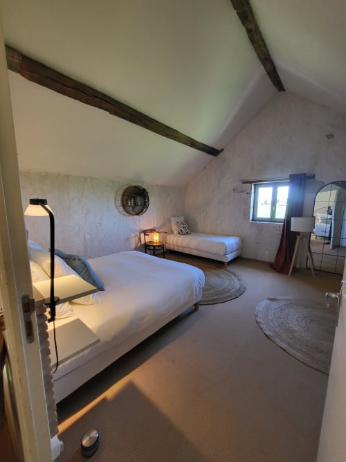 Spacious bedroom in Maison de la Lune cottage at Domaine Des Forges De La Vache, featuring two beds and rustic beams