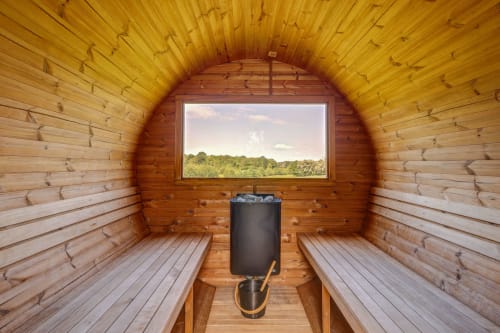 Interior of wooden barrel sauna at Domaine Des Forges De La Vache cottage in Raveau, France, with window overlooking forest
