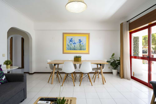 Sala de jantar moderna no apartamento DINIS do hotel RB Algarve em Vilamoura com mesa de madeira, cadeiras brancas e vista para a piscina