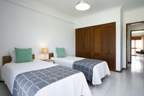 Quarto duplo do hotel RB Algarve em Vilamoura com camas geminadas, almofadas verdes, guarda-roupa em madeira e comodidades modernas