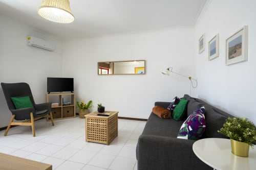 Sala de estar moderna do apartamento RB Algarve em Vilamoura com sofá chumbo, poltrona, TV e mobiliário contemporâneo