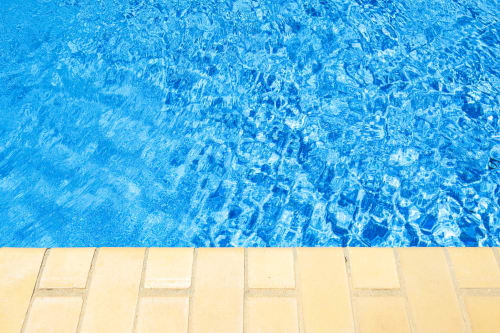 Água cristalina azul da piscina do hotel RB Algarve em Vilamoura, com borda de deck em azulejos bege