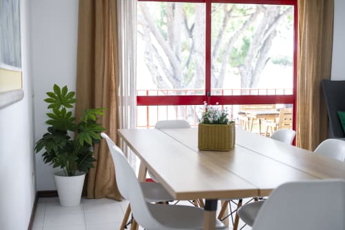 Área de jantar moderna em RB Algarve Vilamoura com mesa branca, cadeiras, planta em vaso e vista para piscina através de grandes janelas