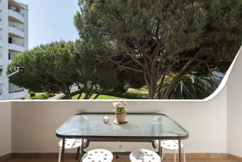Área de estar na varanda do apartamento Pedro da RB Algarve com vista para o jardim e árvores maduras em Vilamoura