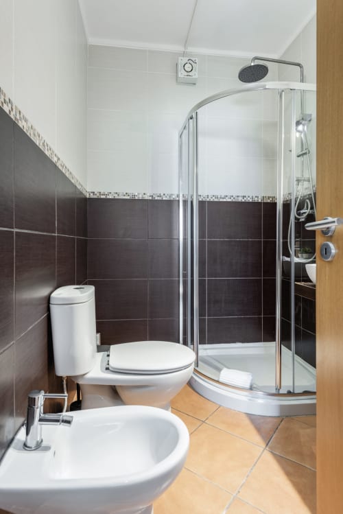 Banheiro moderno no apartamento PEDRO do RB Algarve, Vilamoura com azulejos escuros, chuveiro tipo chuva e louças brancas