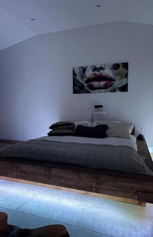 Chambre moderne au Mas Aurel de Provence avec lit en bois foncé, décor noir et blanc, et œuvre d'art contemporain au-dessus