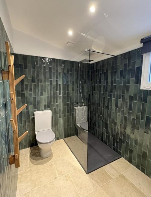 Salle de bain moderne de l'appartement Le Cabanon Secret avec murs carrelés vert foncé, douche spacieuse, toilettes blanches et carrelage beige