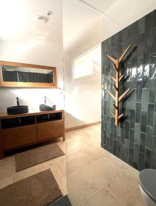 Salle de bain moderne avec douche aux carrelages sombres, vasques noires sur meuble bois, porte-serviettes bois à Le Mas Aurel de Provence