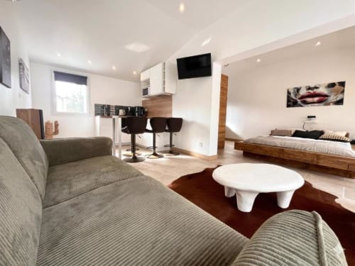 Studio moderne au Mas Aurel de Provence avec canapé, kitchenette, lit et table ronde blanche sur tapis marron