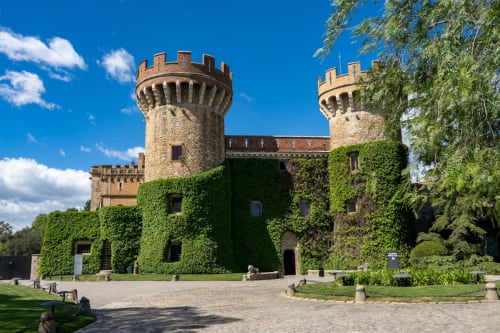 Exterior del castell medieval de l'Hotel de la Font Perelada a Peralada, Girona, amb torres de pedra cobertes de vellut sota cel blau