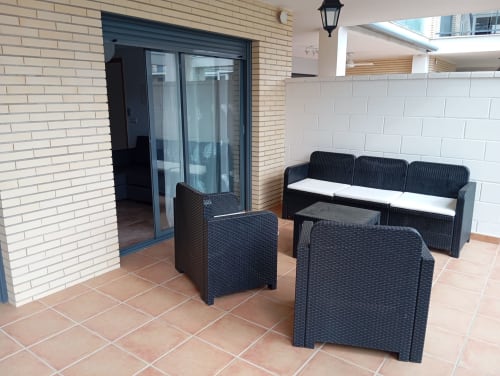Terrasse moderne avec mobilier en rotin noir et coussins blancs à l'appartement Home Guardian Services à Sant Jordi, Espagne