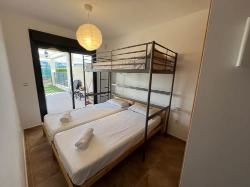 Chambre familiale lumineuse aux Services Home Guardian Sant Jordi avec lits superposés, accès terrasse et luminaires suspendus
