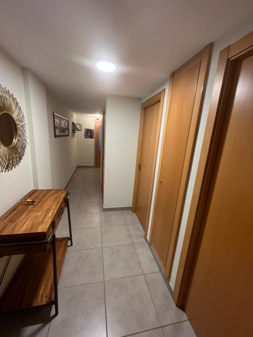 Couloir moderne à Sant Jordi avec portes en bois, carrelage et murs blancs près de l'entrée