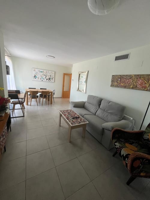 Séjour lumineux avec canapé gris, table à manger et carrelage dans l'appartement Sant Jordi avec vue sur les montagnes