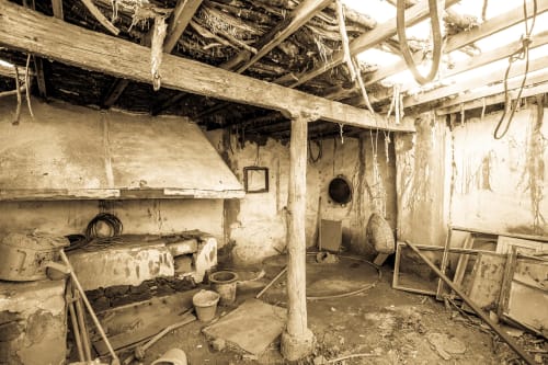 Interior rústico abandonado con vigas de madera, paredes deterioradas y herramientas dispersas en Hotel Rural El Cabo, Villaverde