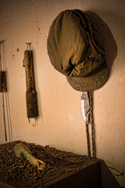 Gorra militar desgastada y cuerda colgadas en la pared del Hotel Rural El Cabo en Villaverde, España