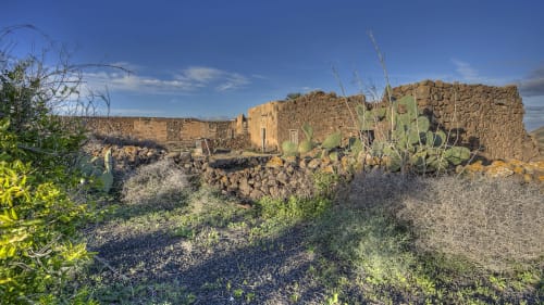 Ruinas de piedra rústica del Hotel Rural El Cabo en Villaverde, España, con vegetación desértica y cielo azul despejado
