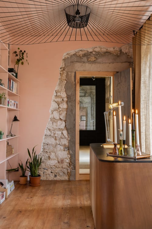 Moulin Moulin B&B reception area in Dannes featuring salmon walls, exposed stone archway, wooden counter with candlesticks,