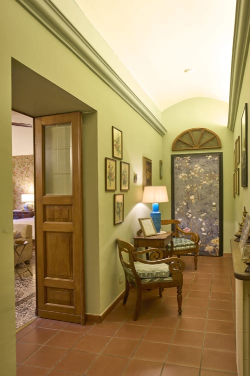 Elegante corridoio della Casa Armenia B&B a Torino con pareti verde salvia, mobili in legno e opere d'arte classica
