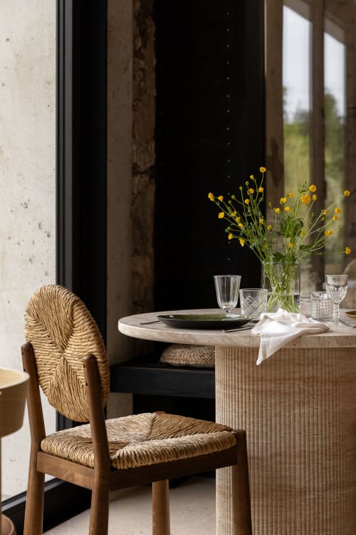 Elegant dining table at Moulin Moulin B&B in Dannes with woven chair, yellow flowers, and countryside views through large
