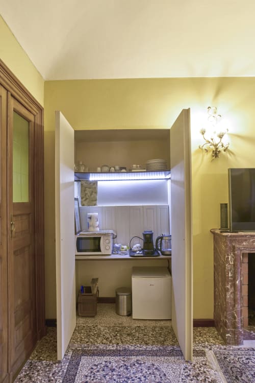 Angolo cottura compatto nell'appartamento Puccini di A Casa Armenia B&B Torino con microonde, frigorifero portatile e elettrodomestici