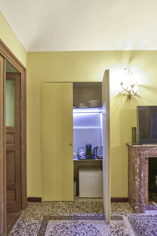Piccola cucina gialla con ripiani illuminati di blu, macchina da caffè e minifrigo nell'appartamento di Torino