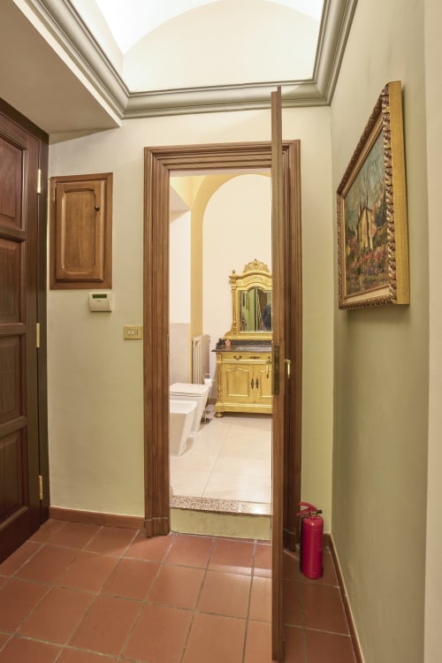Elegante corridoio con porte in legno e lucernario che conduce al bagno con vanity giallo vintage a Casa Armenia B&B Torino