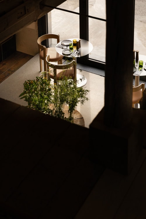 Sunlit dining area at Moulin Moulin B&B in Dannes with round white table, wooden chairs, and potted herbs