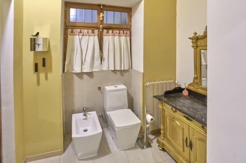 Bagno giallo brillante presso A Casa Armenia B&B a Torino con wc bianco moderno, bidet, lavabo e specchio dorato ornamentale