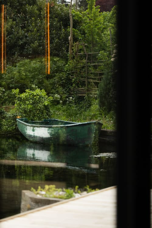Abandoned green boat moored in tranquil garden pond at Moulin Moulin B&B, Dannes, France