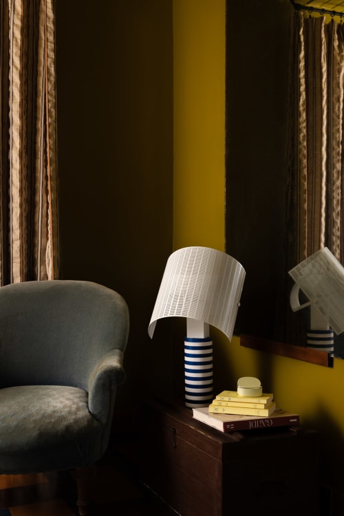 Cozy reading nook at Moulin Moulin BnB in Dannes with armchair, striped lamp, and stacked books