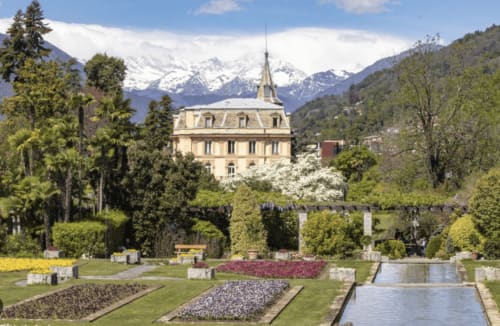 Lussuoso ritiro termale a Stresa con giardini curati, vasca riflettente, sfondo delle Alpi innevate