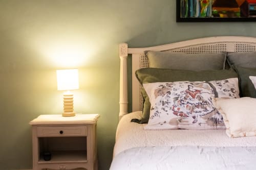 Cozy bedroom at Le Jardin Secret cottage in Grignan with rattan headboard, white linens, and bedside lamp