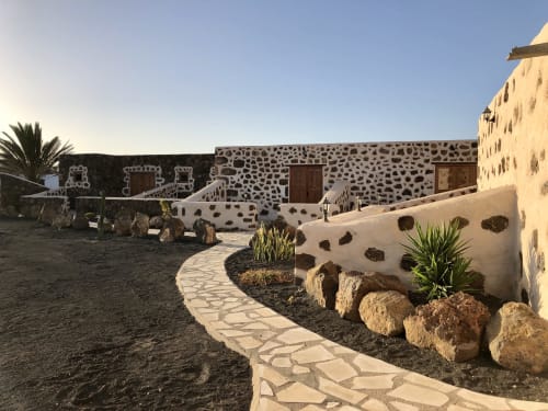 Patio del Hotel Rural El Cabo en Villaverde con construcciones encaladas, muros de piedra volcánica y jardines desérticos