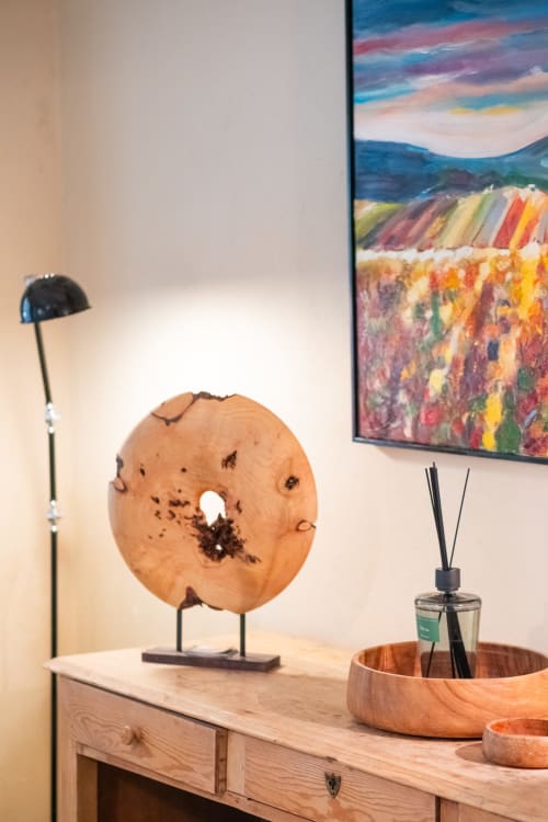 Stylish cottage décor at Le Jardin Secret with wooden desk, abstract art, and decorative wood bowl