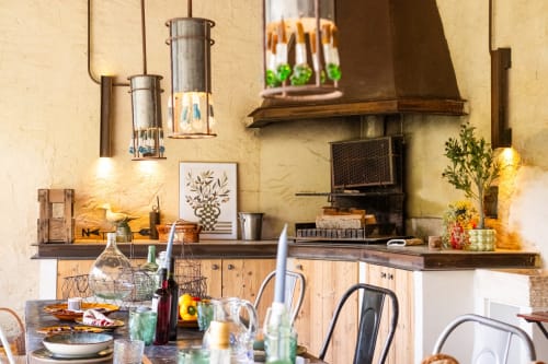 Rustic kitchen with stone walls, wooden cabinets, and dining area at Le Jardin Secret cottage, Grignan