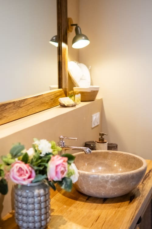 Luxury bathroom sink with marble bowl at Le Jardin Secret cottage in Grignan, featuring fresh flowers and brass fixtures