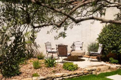 Tranquil garden seating area at Le Jardin Secret cottage in Grignan with lounge chairs, fire pit, and olive tree shade