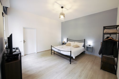 Modern bedroom in LikeHome Mentessi apartment, Ferrara with black metal bed, wooden flooring, pendant light, and city views