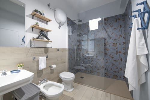 Modern bathroom in LikeHome Mentessi apartment, Ferrara, with walk-in shower, toilet, bidet, and white sink with wooden