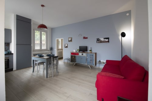 Modern apartment in Ferrara with red sofa, dining table, TV stand, and kitchen with blue accents